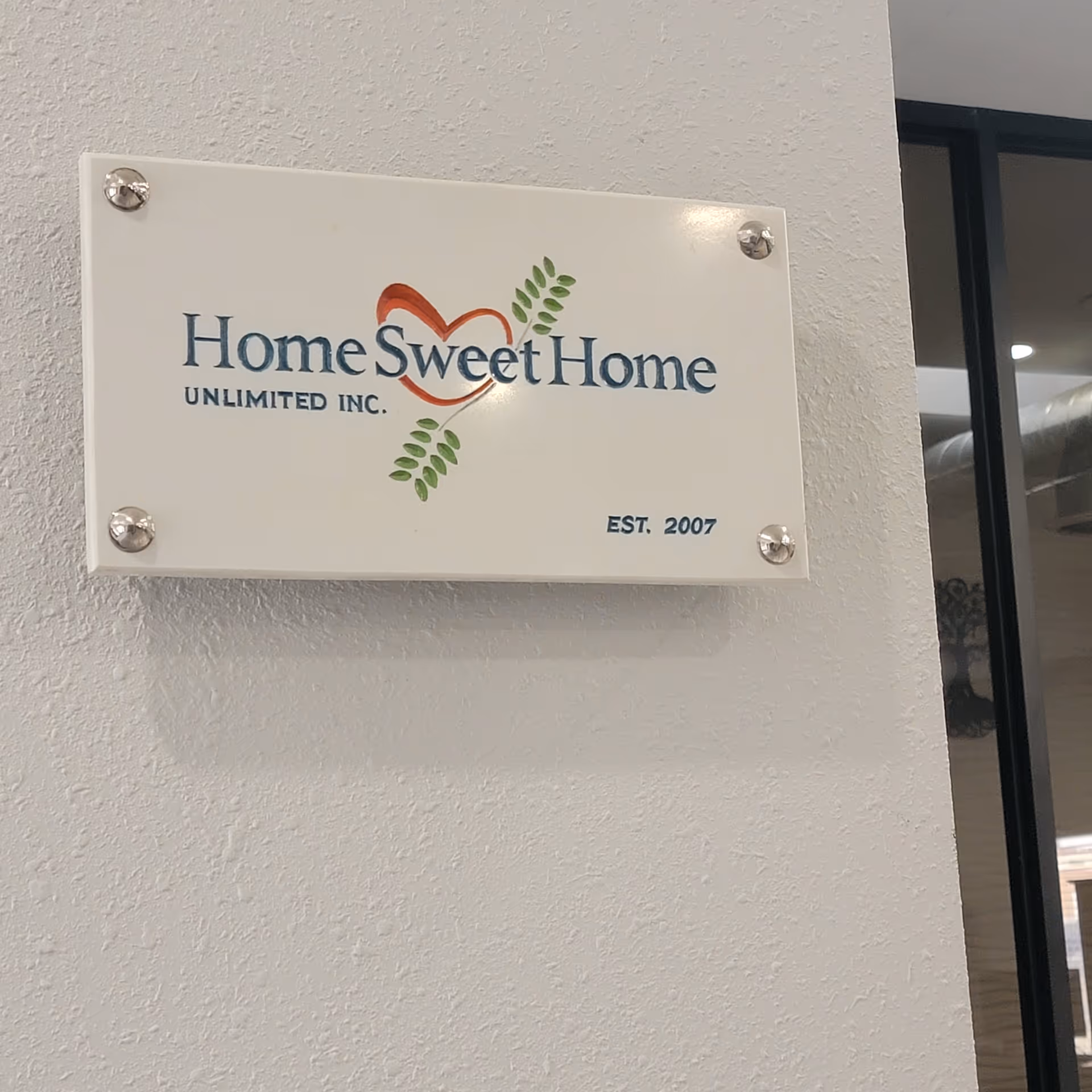 A wall sign reads 'Home Sweet Home Unlimited, Inc.' beside a glass door.