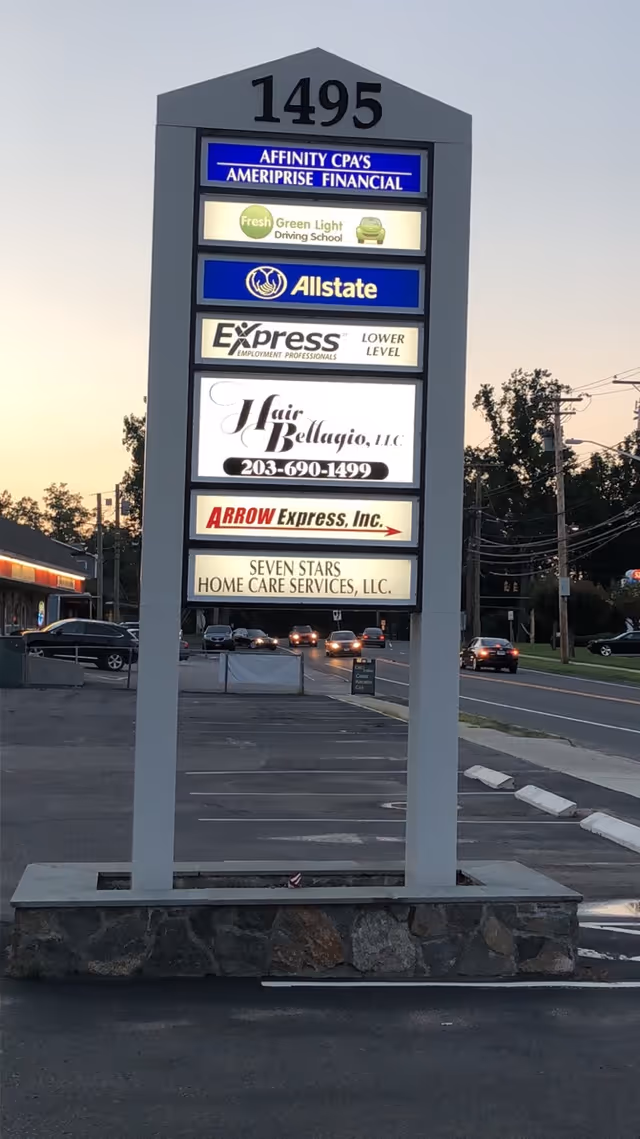 Outdoor signboard with multiple business names, including Seven Stars Home Care Services, in a parking lot.