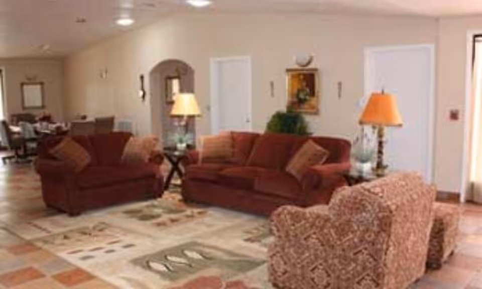 Cozy common living room with red sofas, lamps, and patterned chairs.
