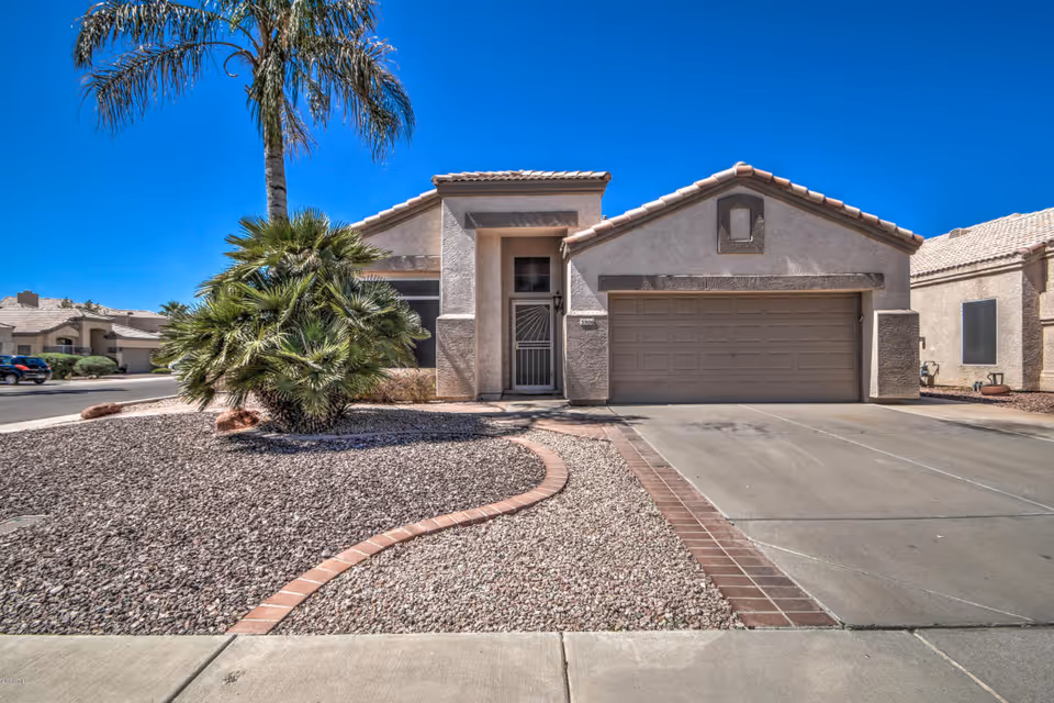 Front view of a desert-style house with a two-car garage and gravel landscaping.