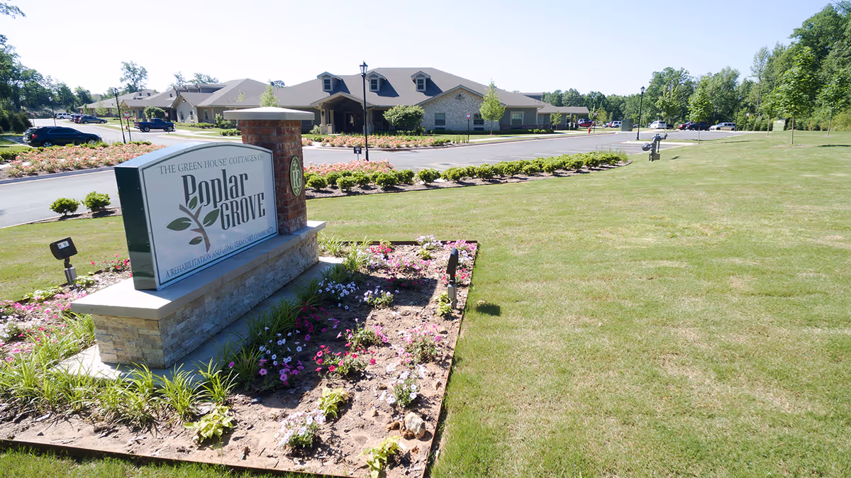 Exterior view of The Green House Cottages of Poplar Grove sign with landscaped flower bed
