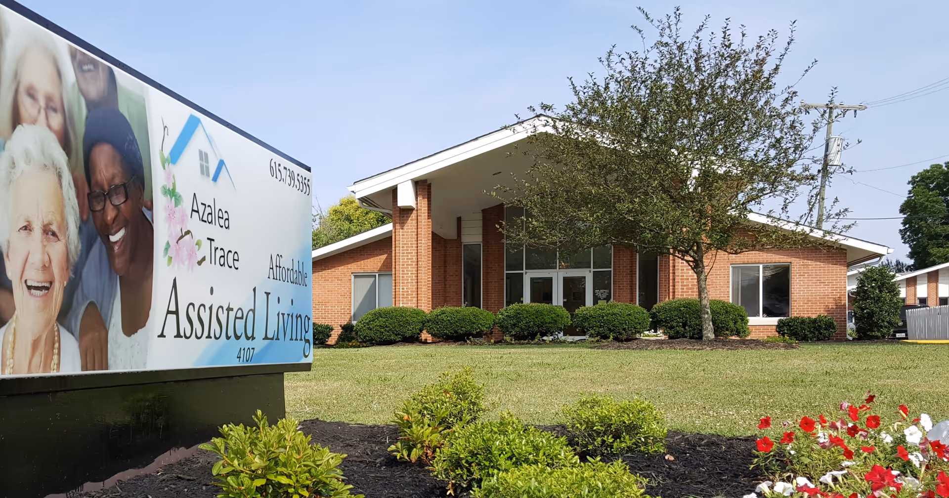 Front entrance of a brick assisted living building with landscaping and a large 'Azalea Trace Assisted Living' sign in the foreground.