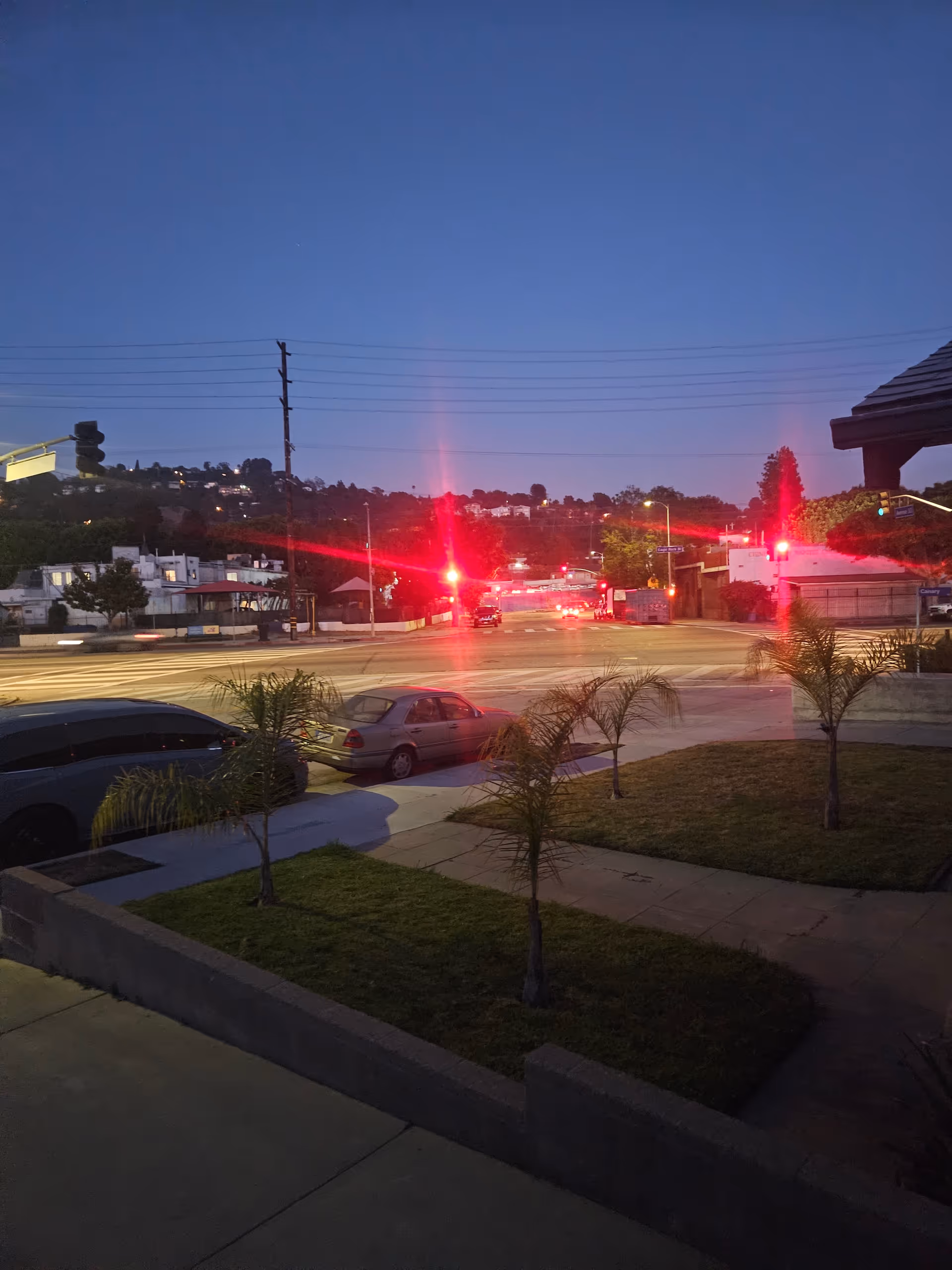 Evening street view with red emergency lights at an intersection near a building.