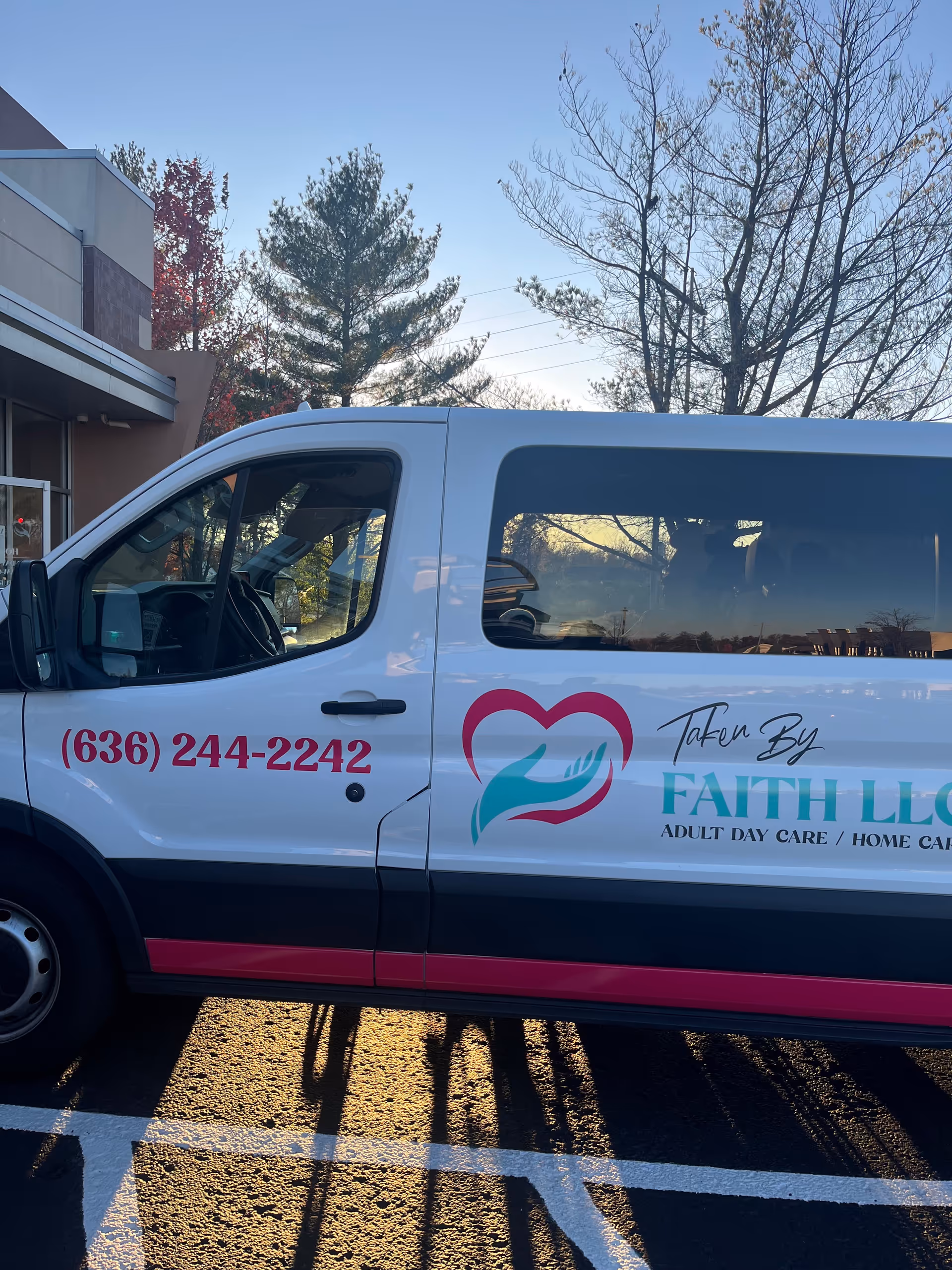 White van with Taken By Faith LLC branding parked outside a building.