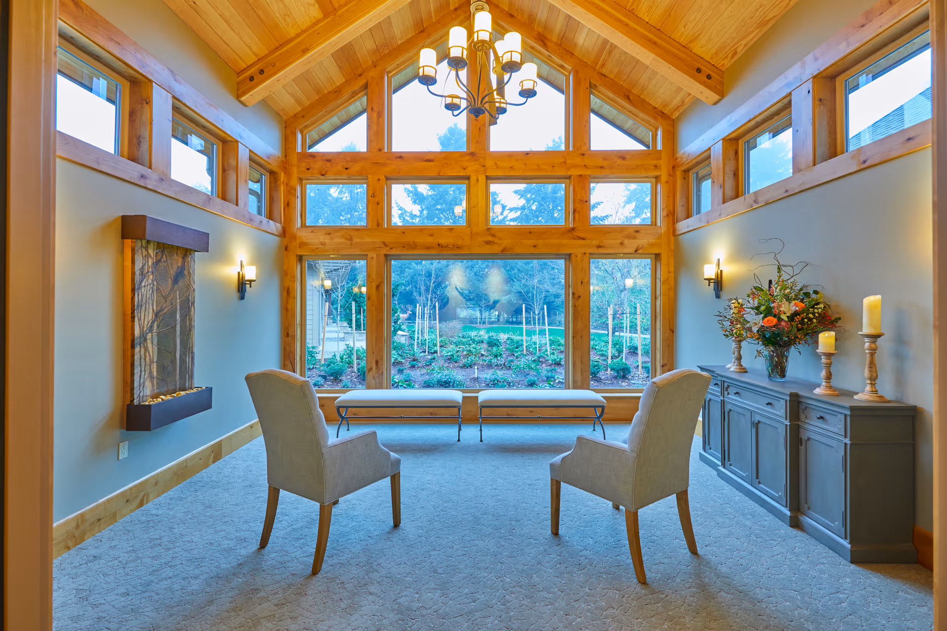 Bright, wood-accented living room with two chairs, bench, and a sideboard by windows.