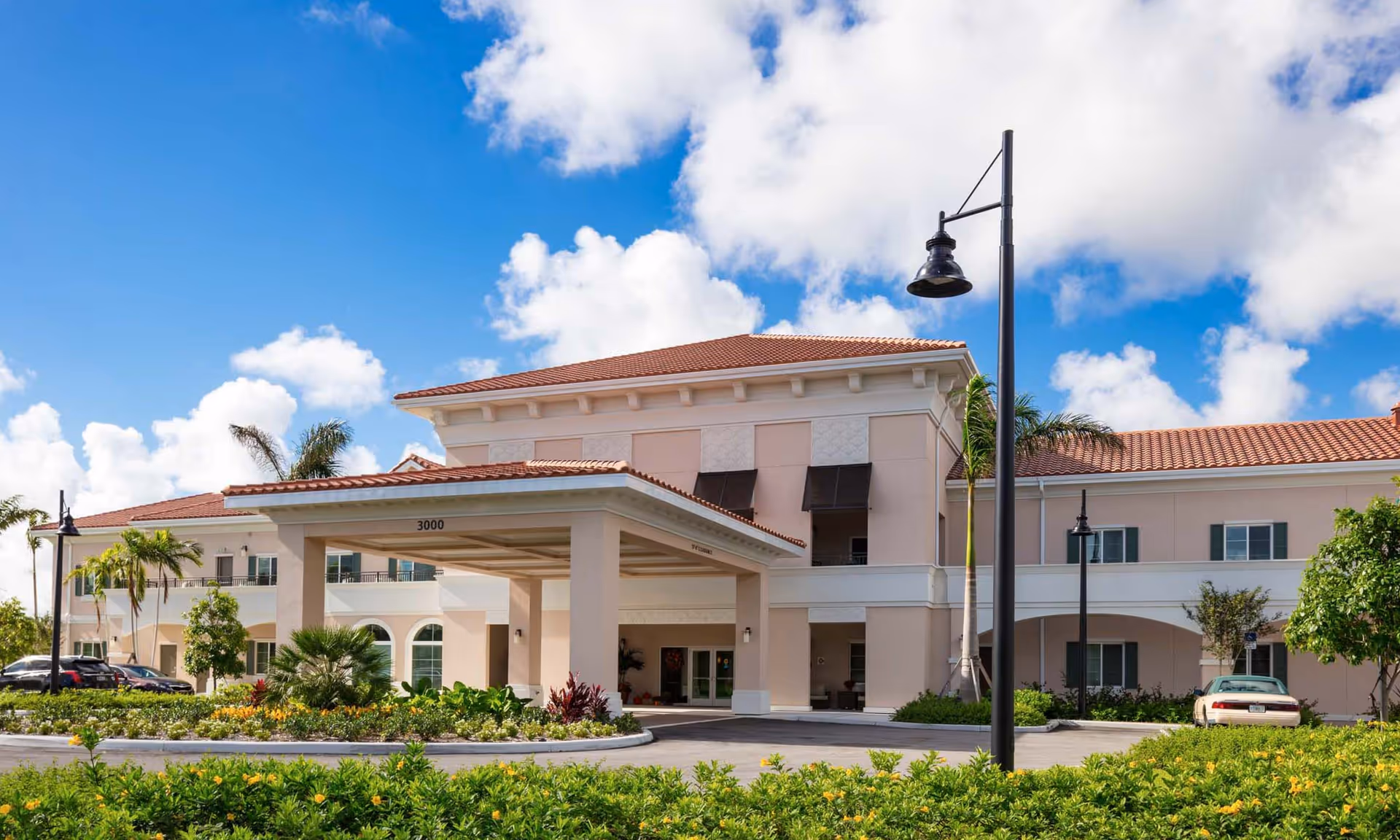 Exterior view of HarborChase of Palm Beach Gardens with porte-cochère entrance and landscaping