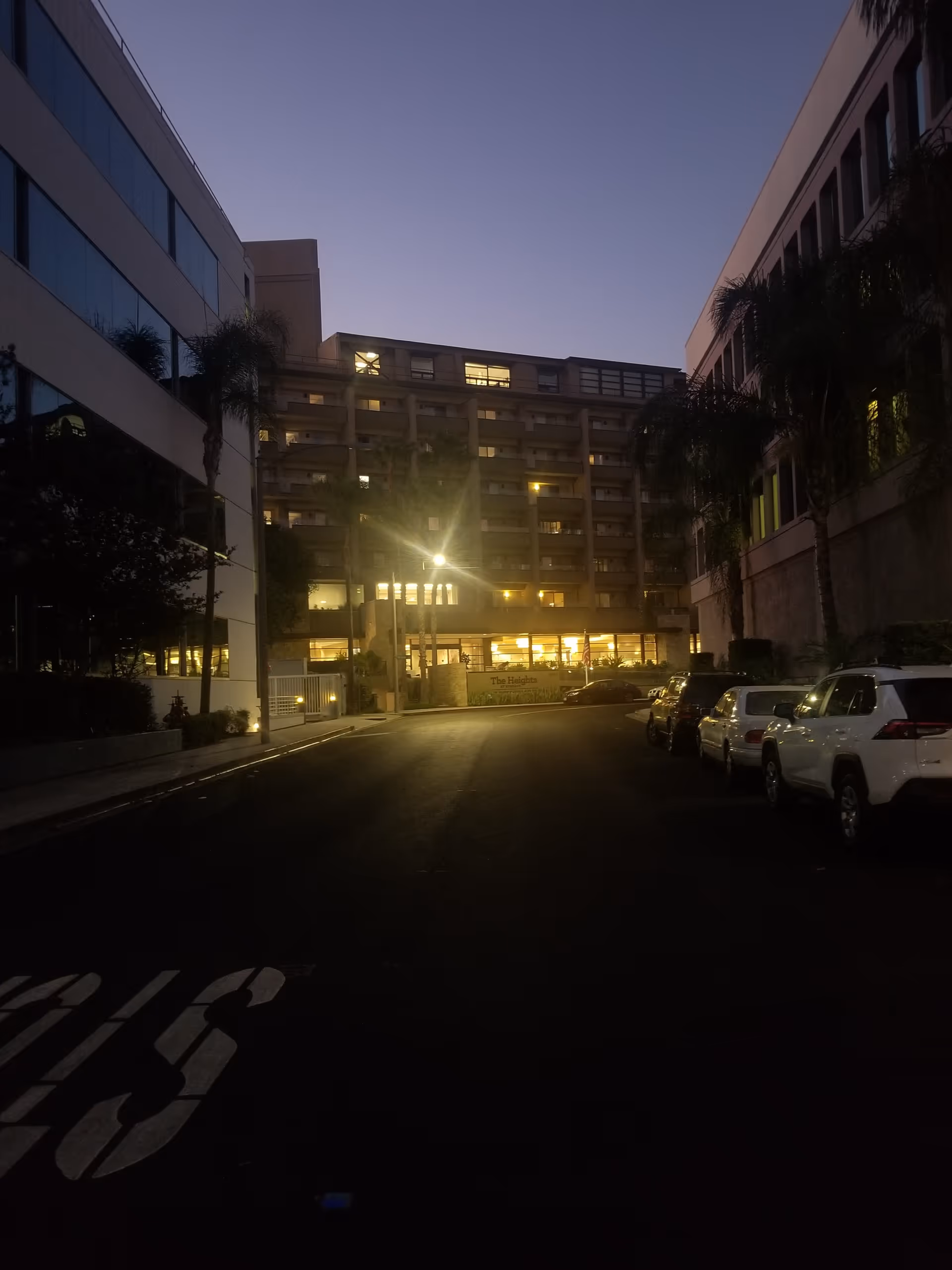 Evening exterior of Ivy Park at Burbank with lit windows and parked cars along the street