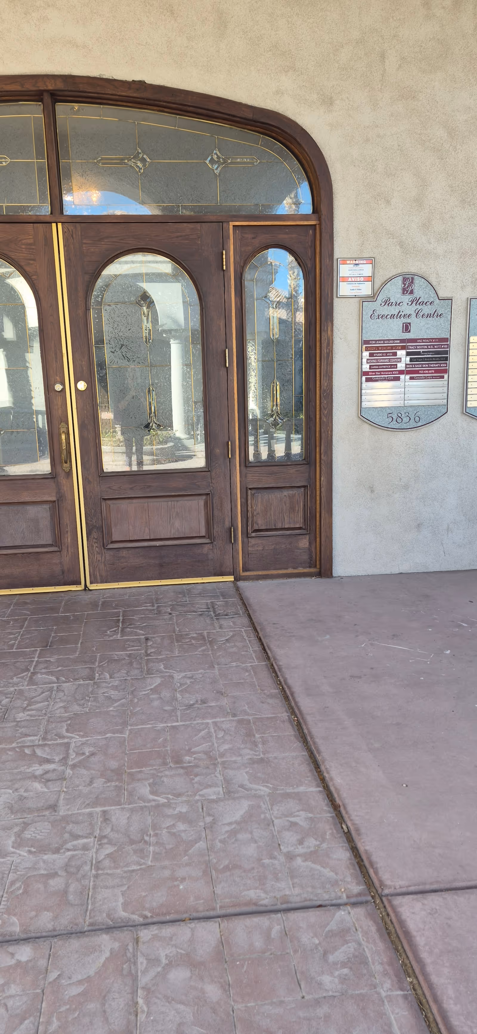 Exterior view of a facility entrance with wooden doors and a sign plaque.