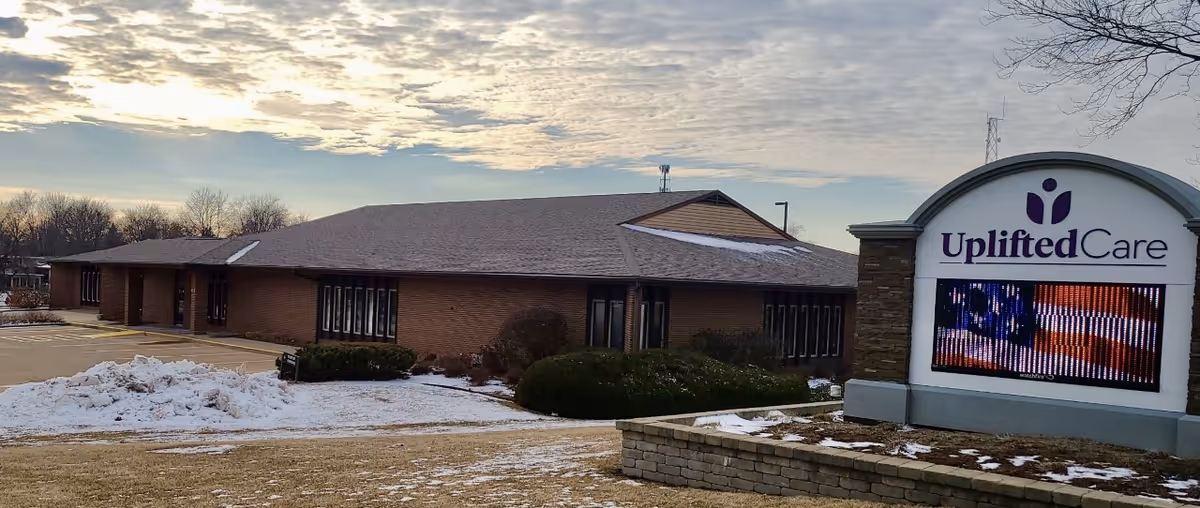 Exterior view of a brick senior living facility with UpliftedCare sign