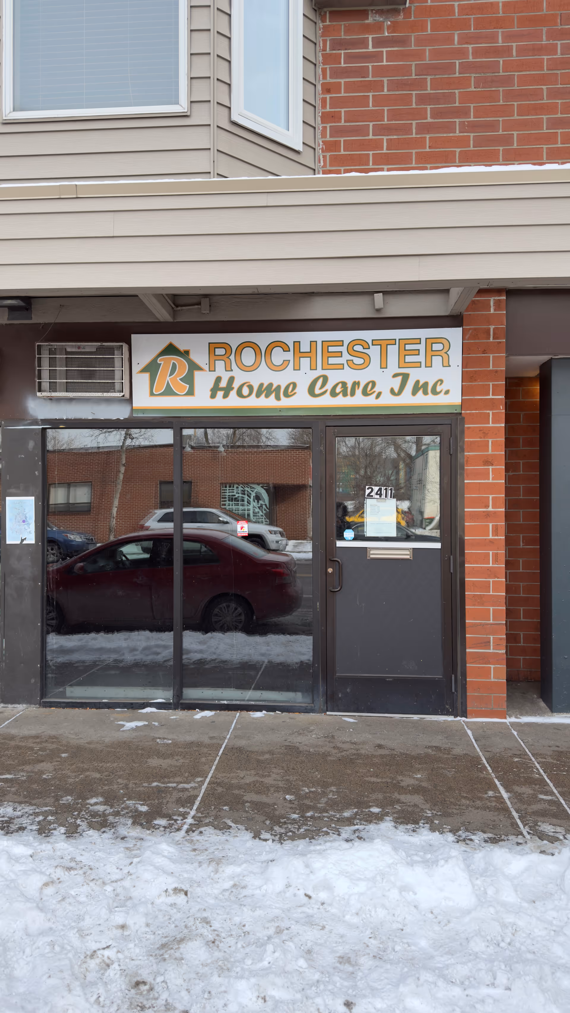 Exterior entrance of Rochester Home Care, Inc., with glass doors and a sign.