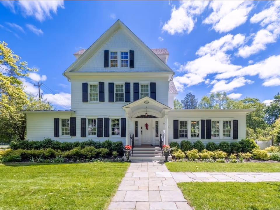 White two-story house-style facility with black shutters on a manicured lawn.