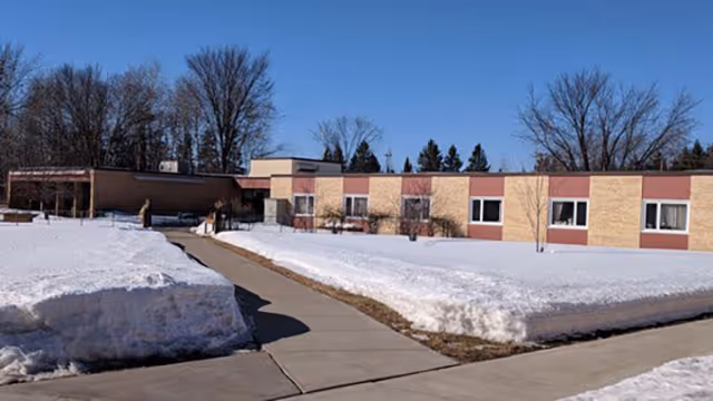Front exterior of a single-story care center with cleared sidewalk and snow.