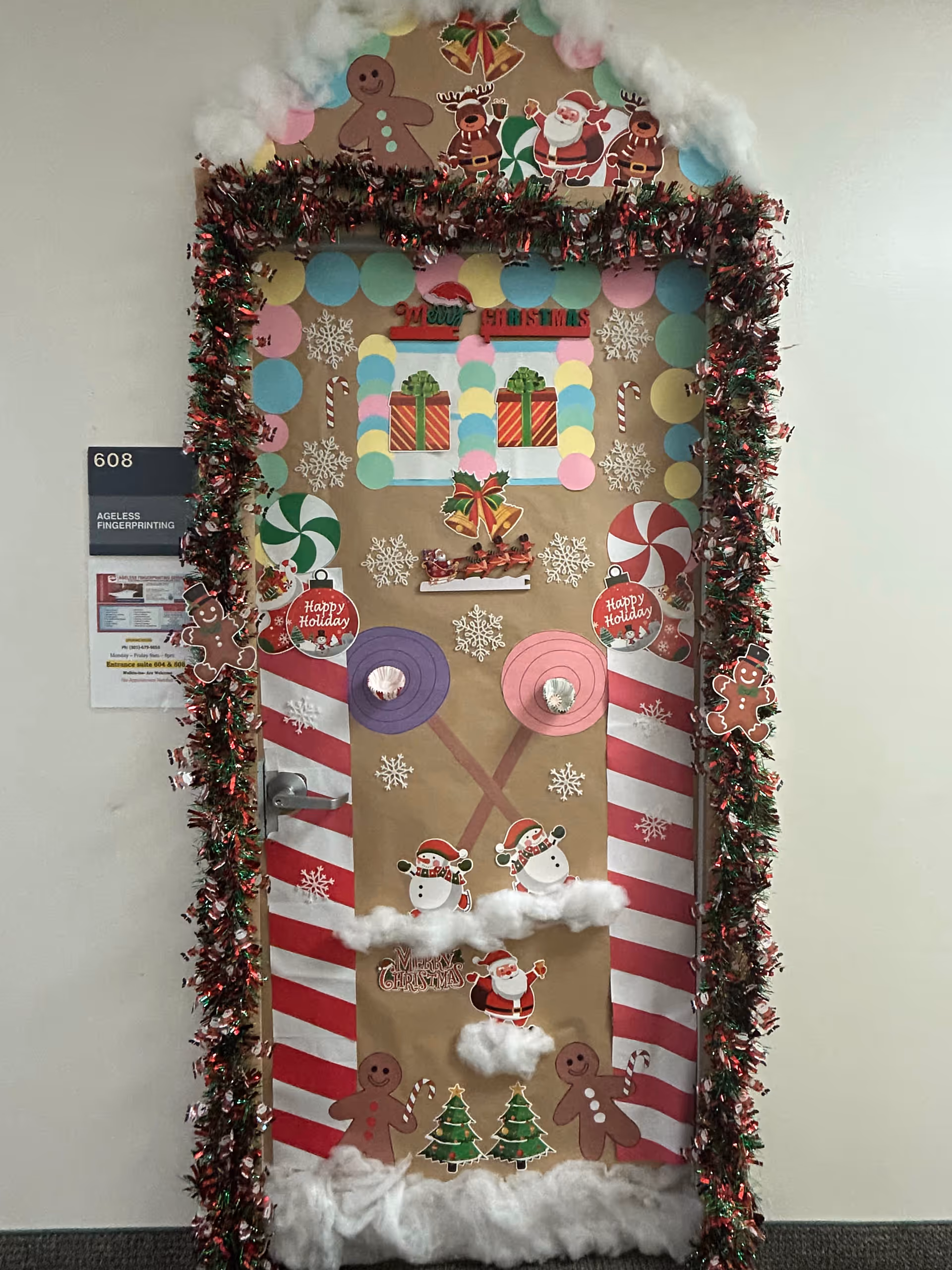 Door decorated for Christmas in a hallway with garland and festive cutouts.
