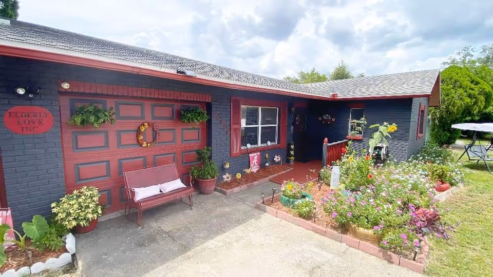 Front view of a dark blue building with red trim and a colorful front garden.