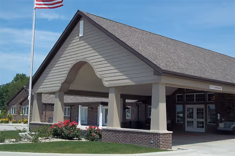 Exterior view of Villas of Holly Brook Shelbyville entrance with arched archway and flag.