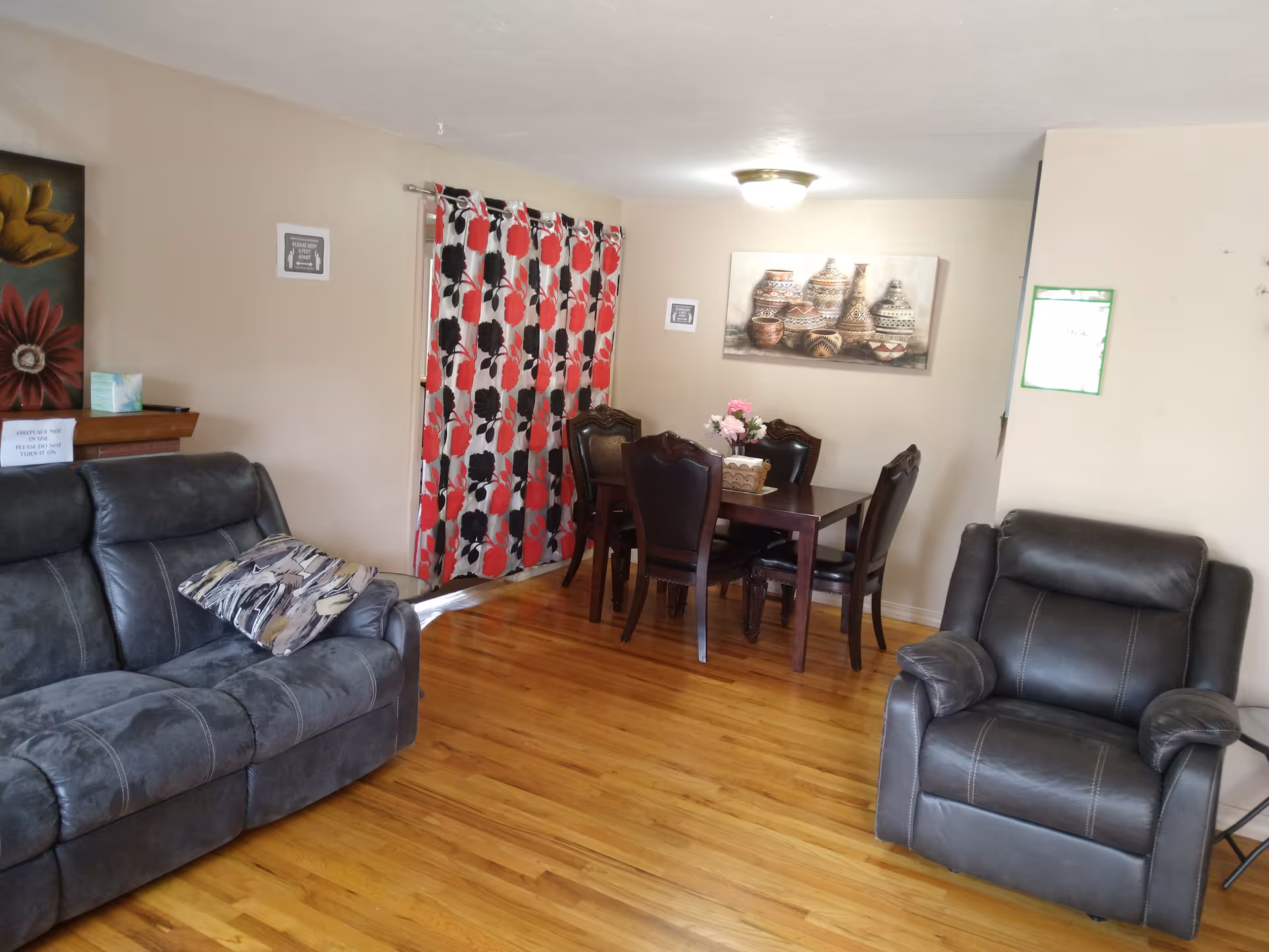 Cozy living room in Ava facility with couches, a dining table, curtains, and wall art.
