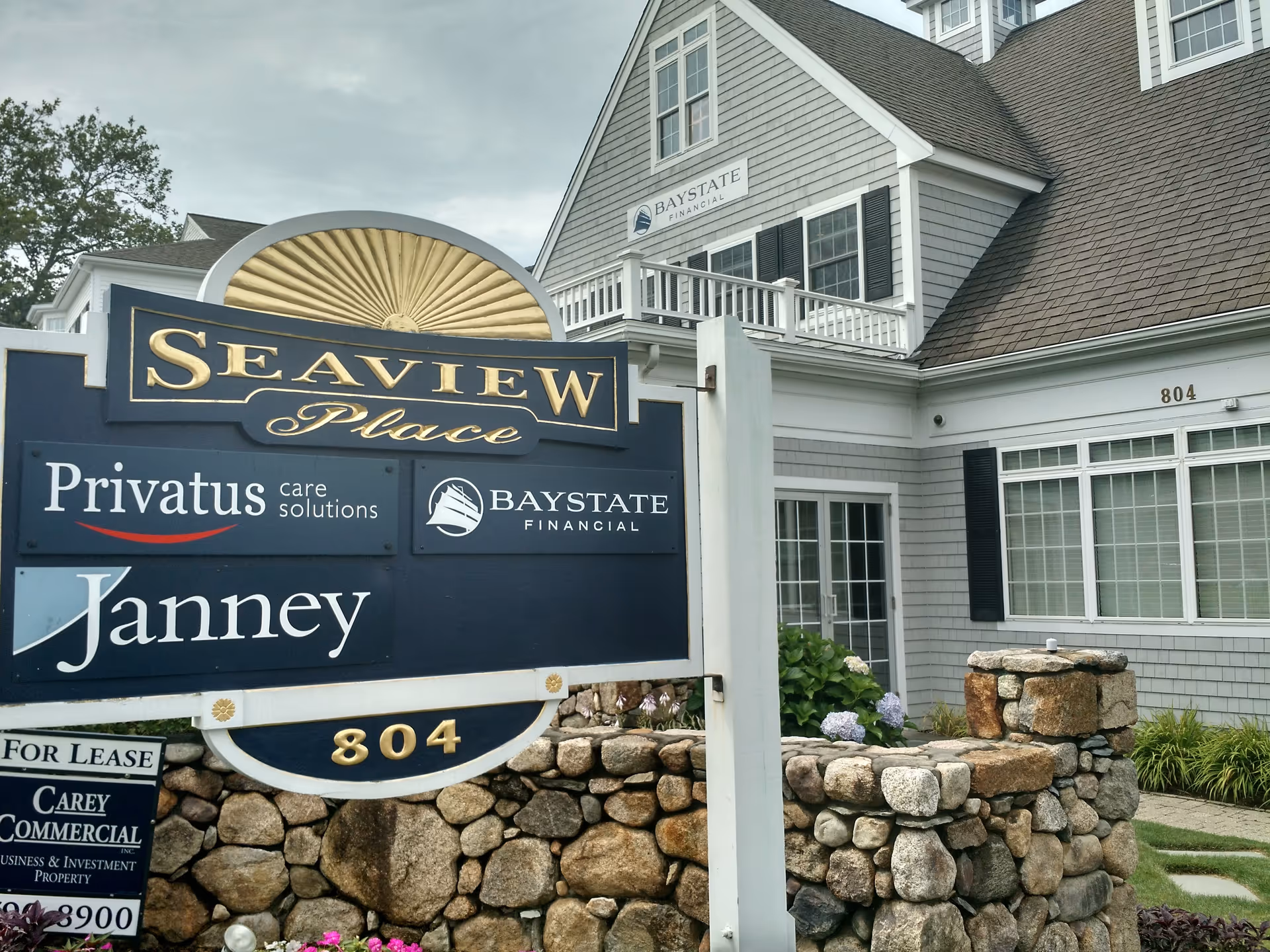 Exterior view of a senior living facility with a Seaview Place sign and stone wall.