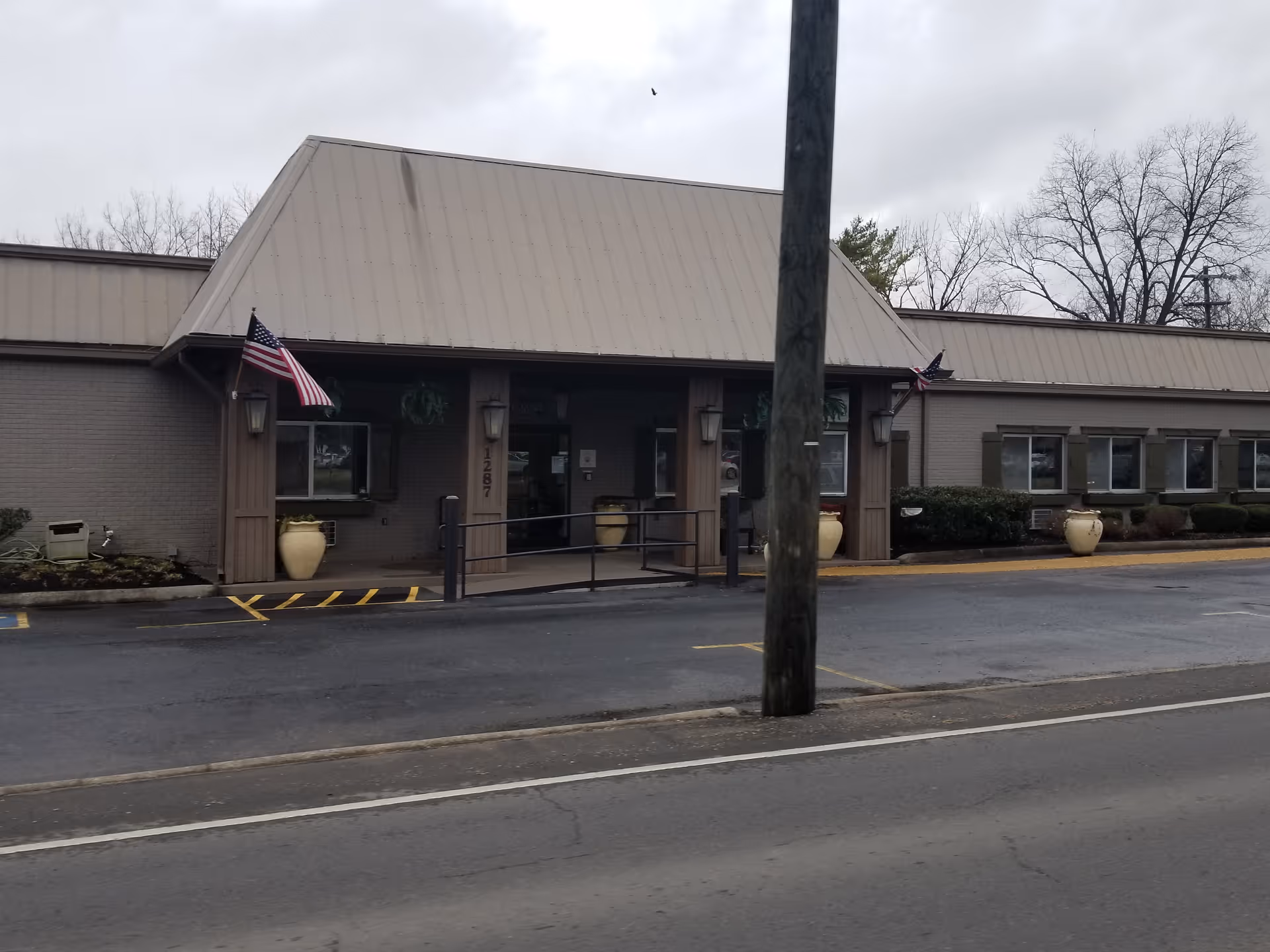 Front exterior of a senior living facility with entrance and flags.
