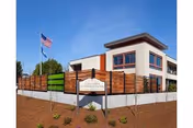 Front exterior of Columbia Lutheran Home with wooden fence, sign, and American flag.