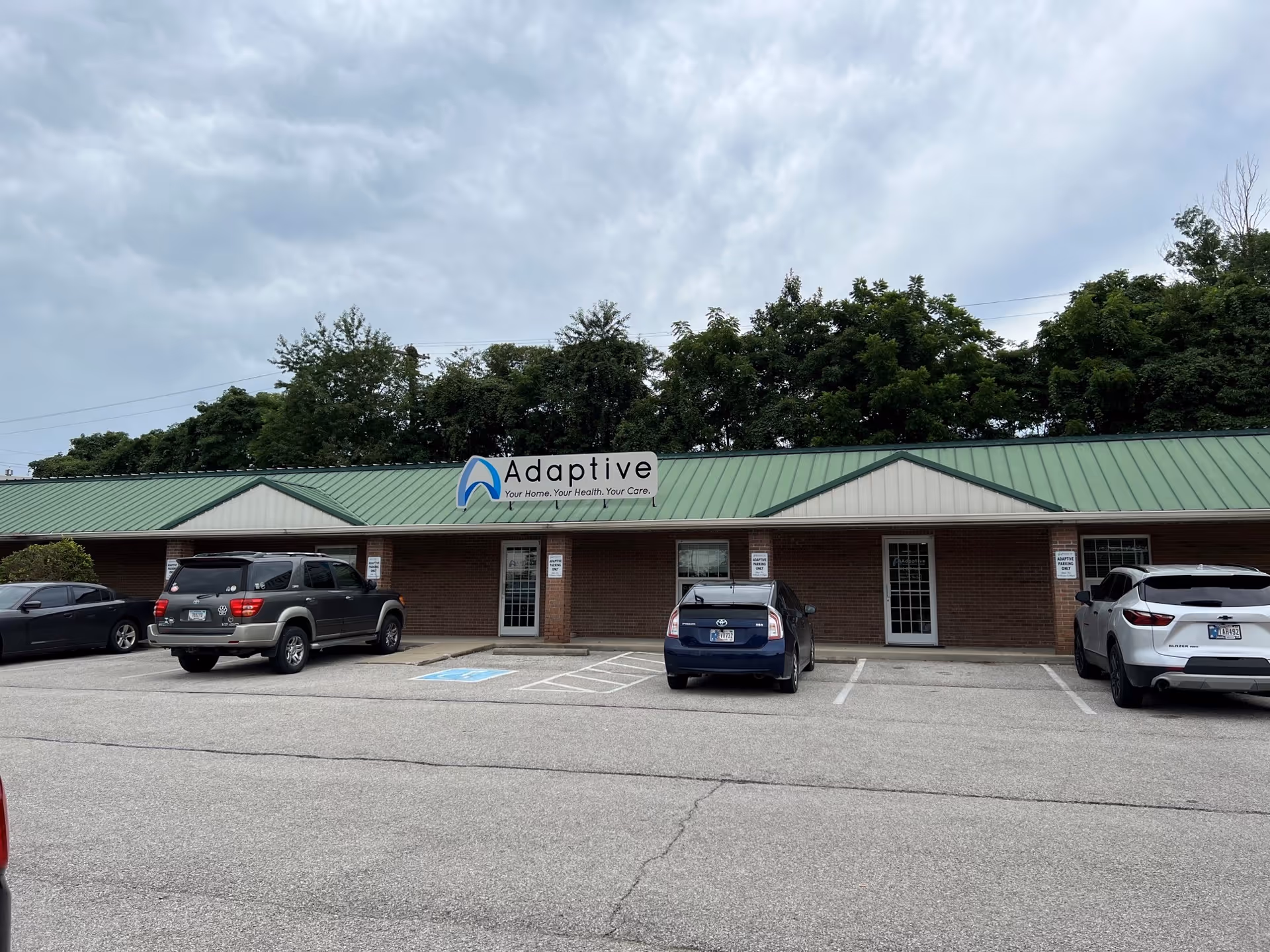 Front view of Adaptive Nursing and Healthcare Services building with parked cars in a lot