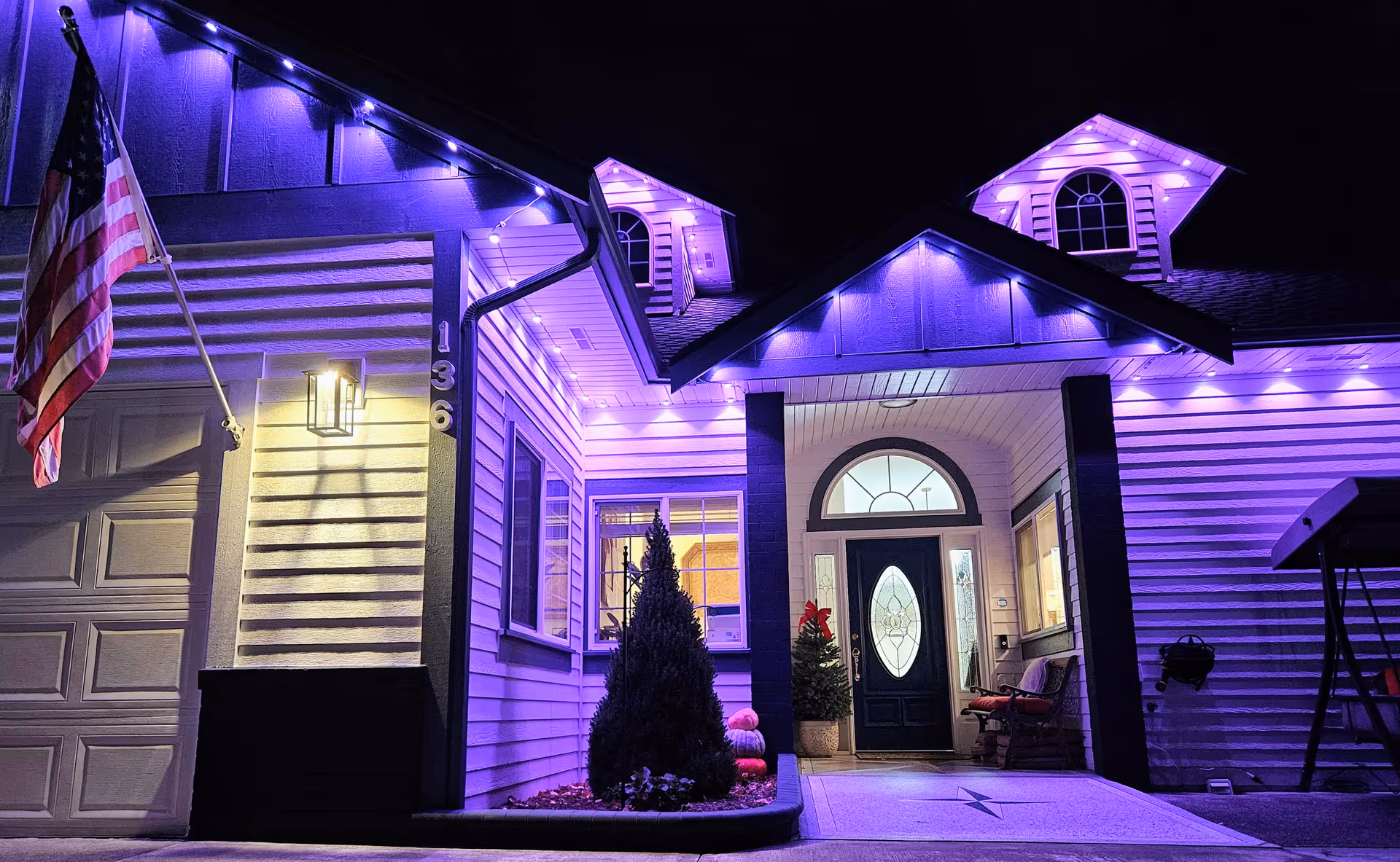 Night exterior of a front entrance lit with purple lights and an American flag.