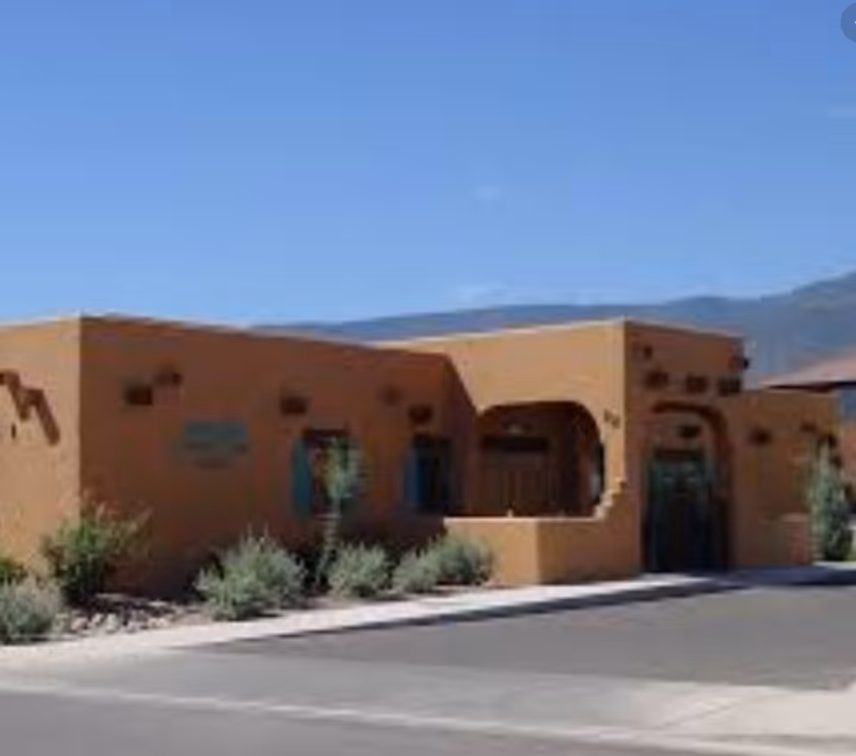 Sunlit adobe-style senior living center exterior with entry arches and desert shrubs.