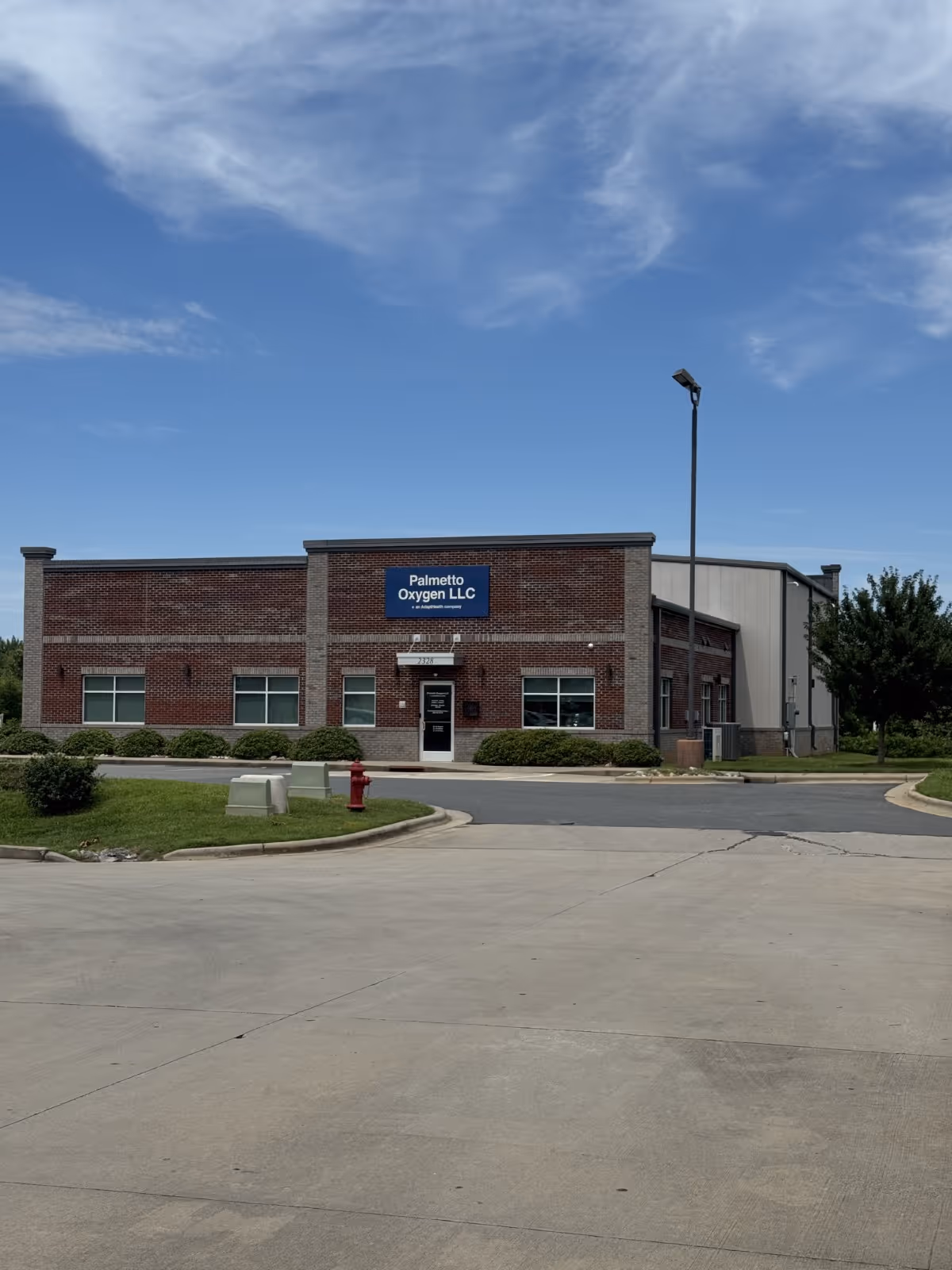 Brick Palmetto Oxygen LLC building fronts a parking lot under blue sky.