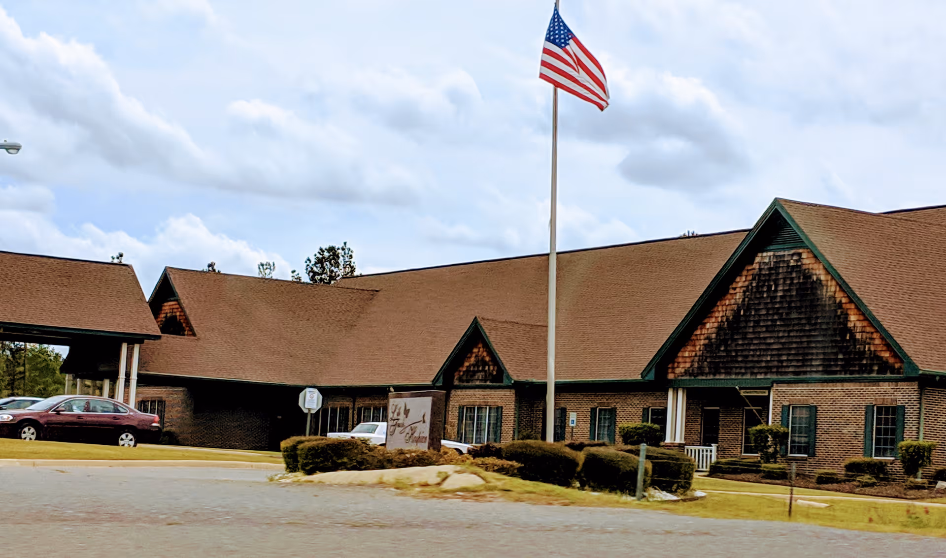 Exterior view of Life Touch Hospice building with flagpole and brick facade.