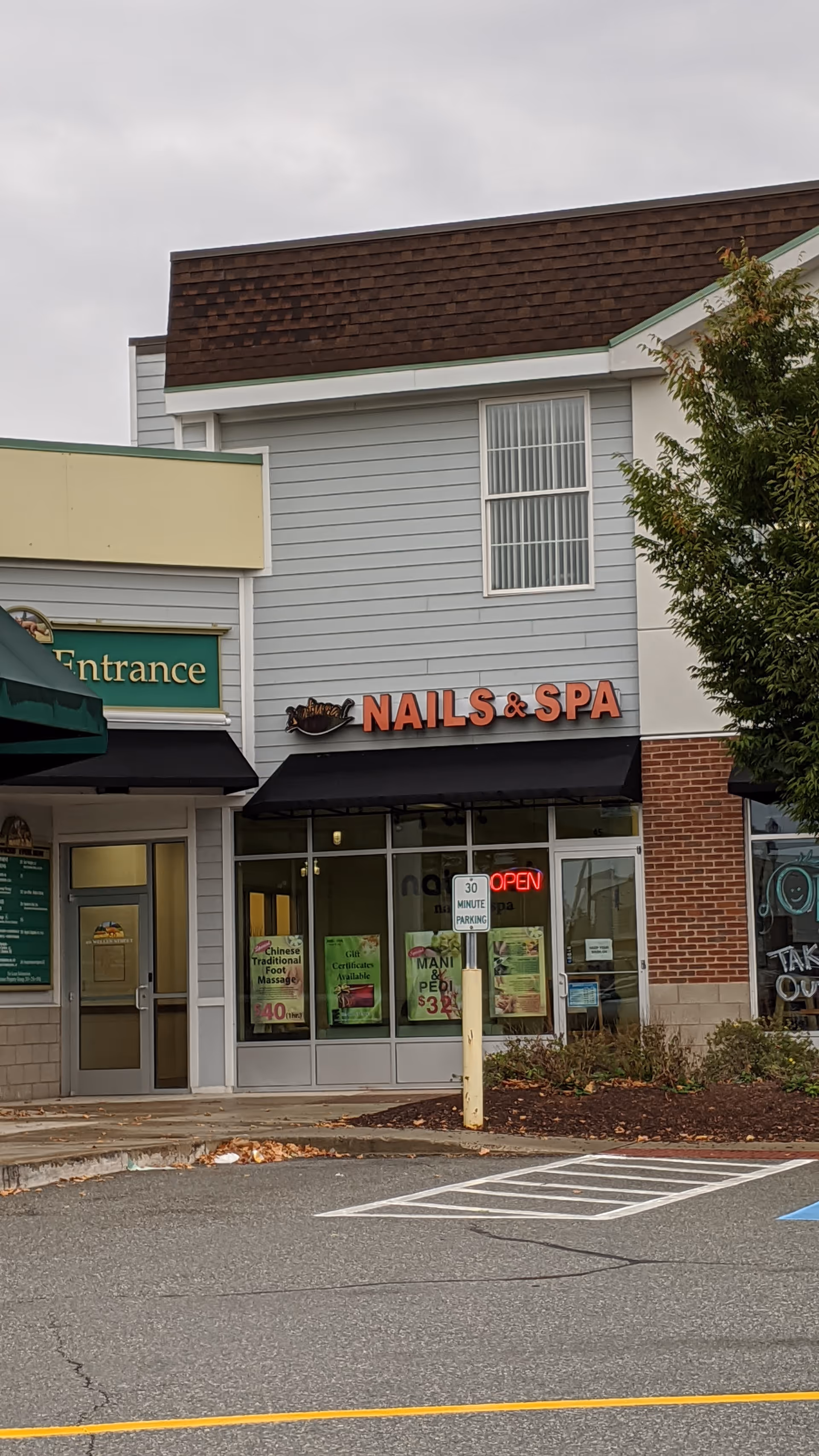 Exterior view of a storefront with nails & spa signage and a parking lot.