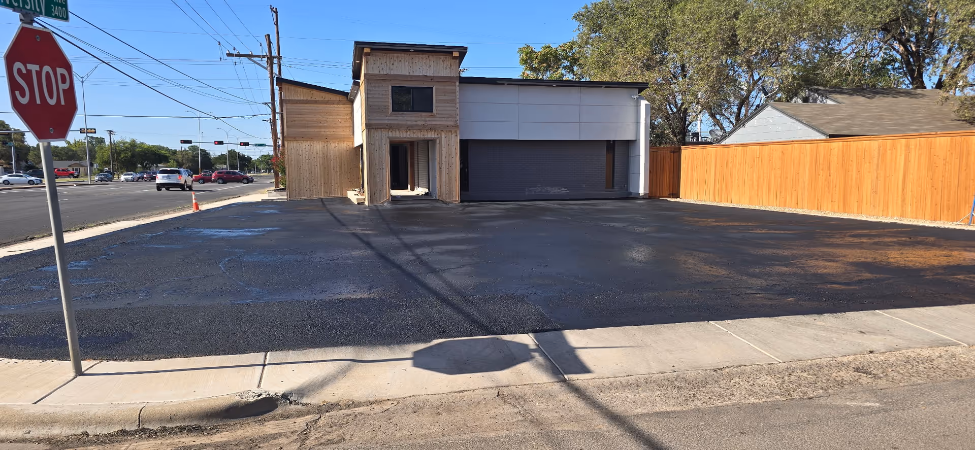 A vacant parking lot in front of a small building under construction, with a stop sign.