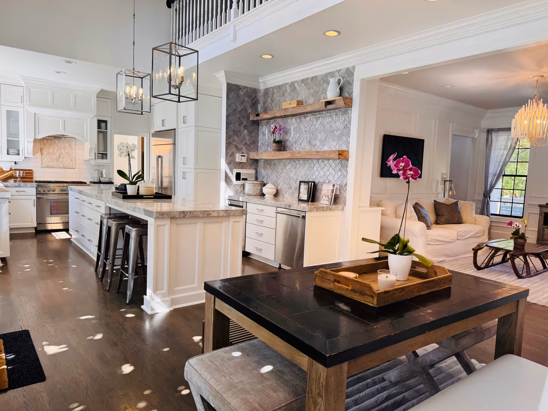 Bright open-concept kitchen with island, white cabinets, and living area in background.