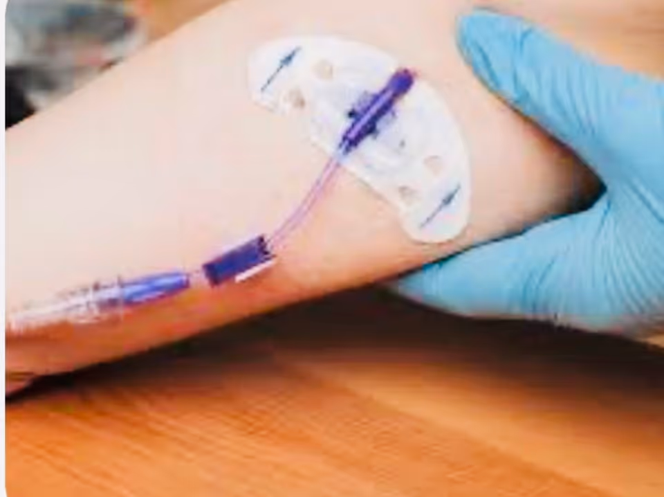 Gloved hand applies an adhesive medical patch to a patient's forearm.