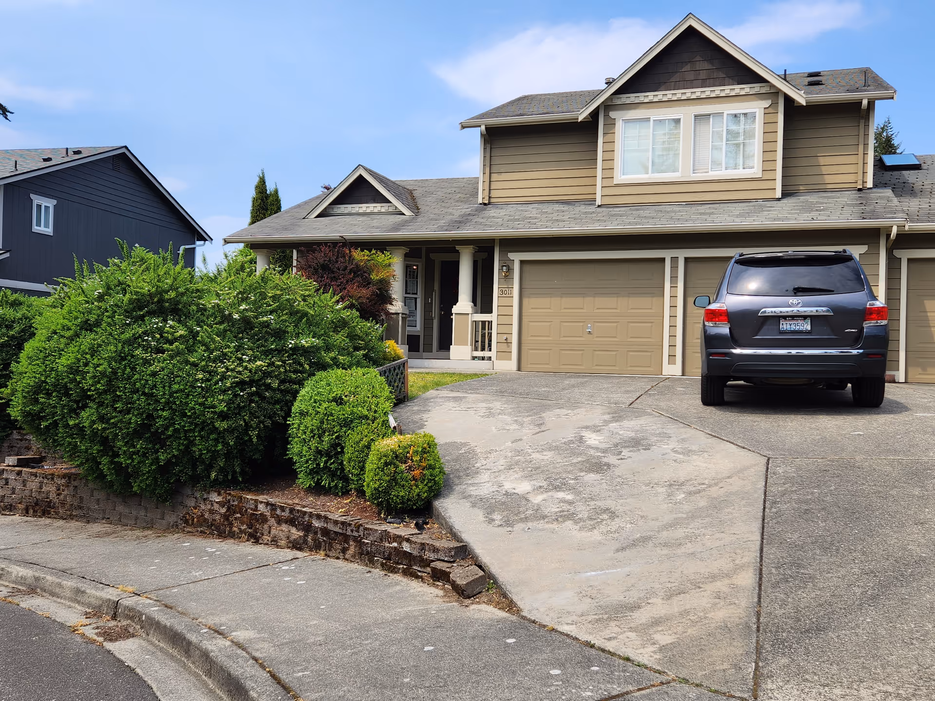 Front view of a beige two-story house with a driveway and a parked SUV.