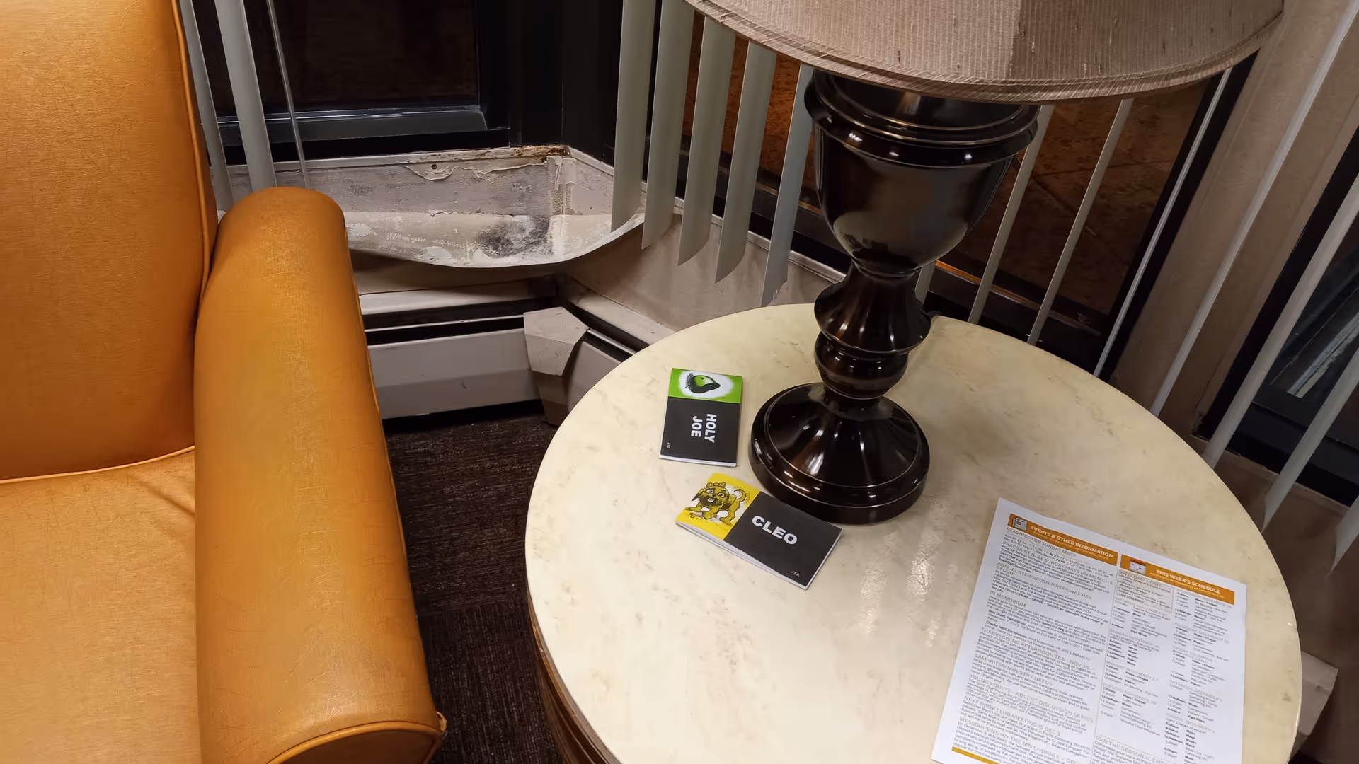 Round light table with lamp beside an orange armchair in a living area