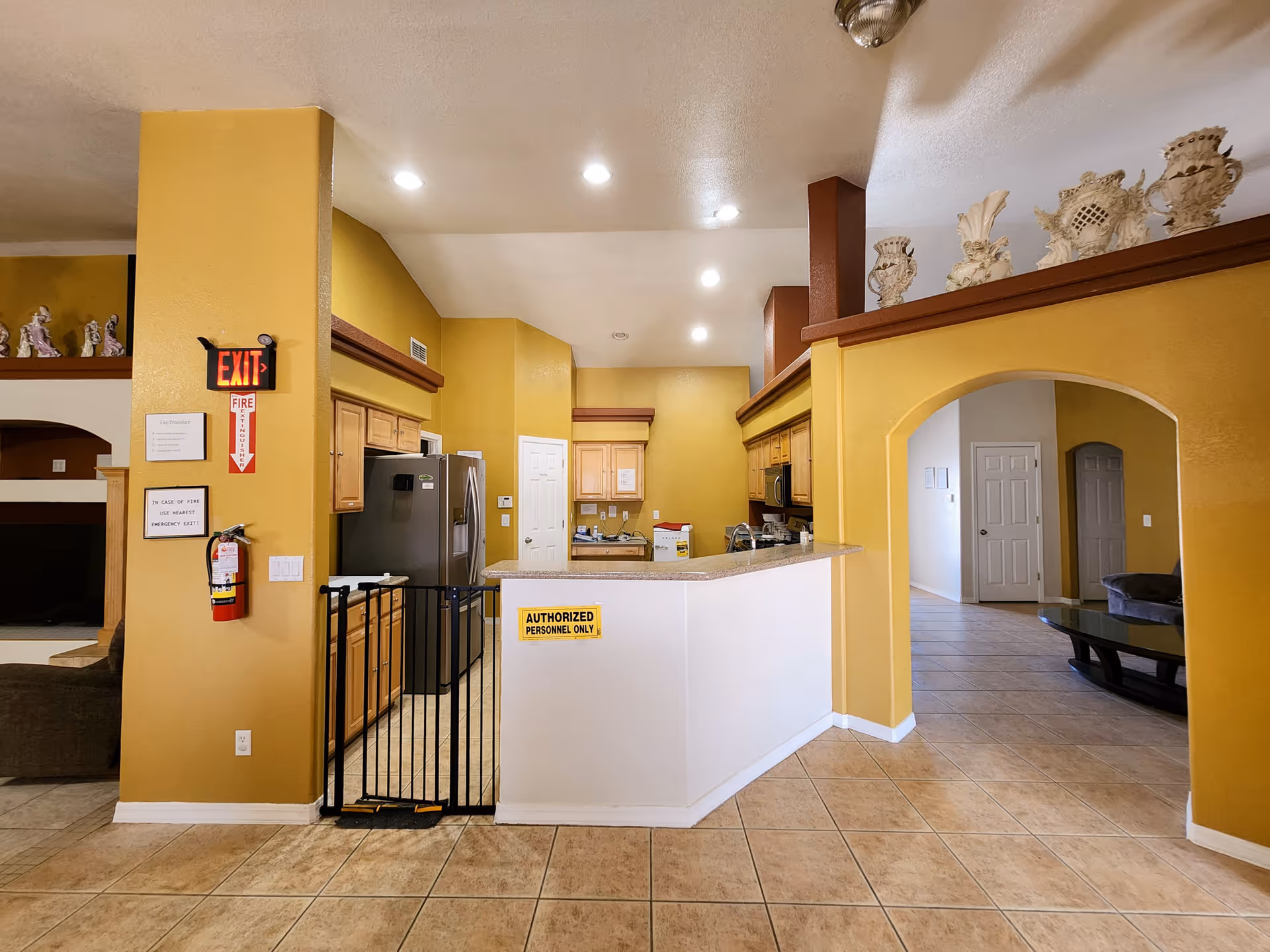 Bright yellow interior lobby with a kitchen counter, archway, and access gate.