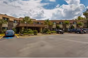 Exterior view of Ashford Gardens senior living facility with parked cars in the lot.