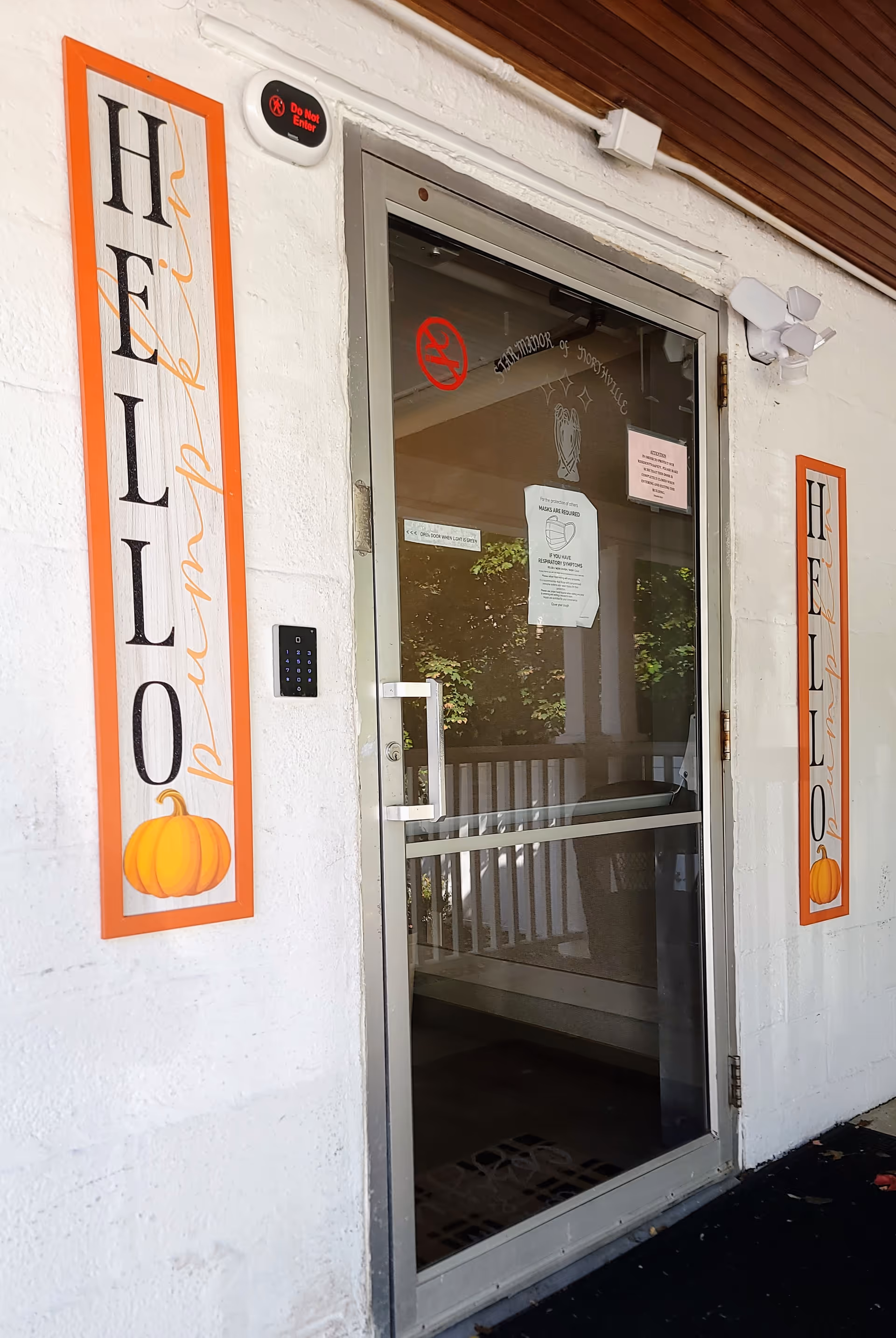 Exterior entrance of Star Manor of Northville with orange Halloween banners beside a glass door.