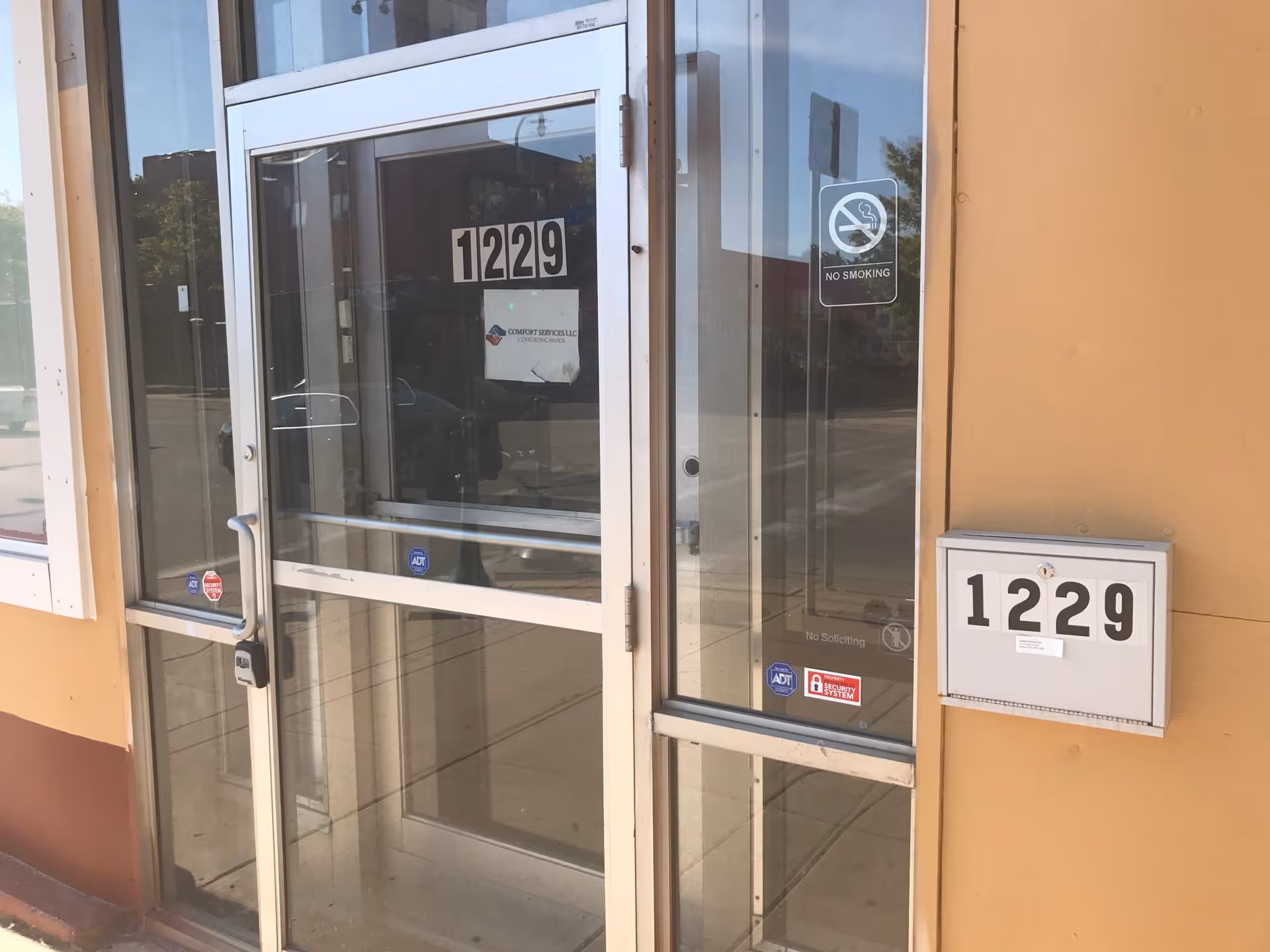 Glass entrance door with '1229' address plaque and mailbox on exterior wall.