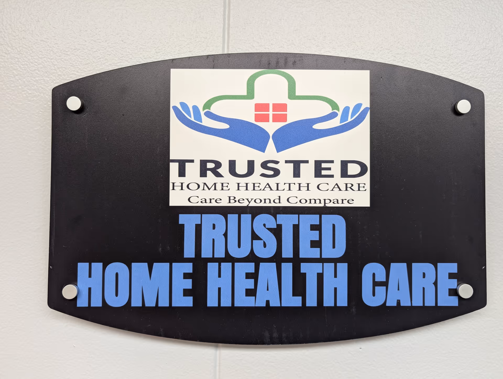 A black exterior sign on a wall shows Trusted Home Health Care with a blue logo.