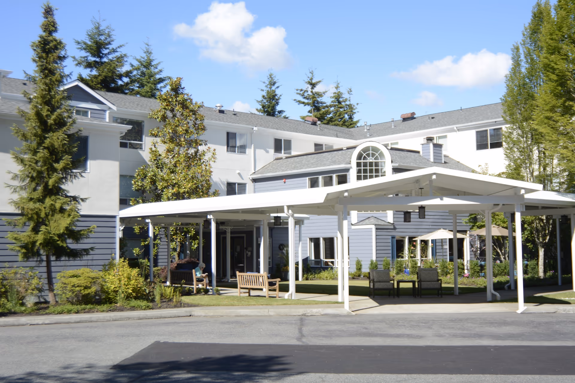 Exterior view of Mountlake Terrace Plaza with a white porte-cochere and seating area