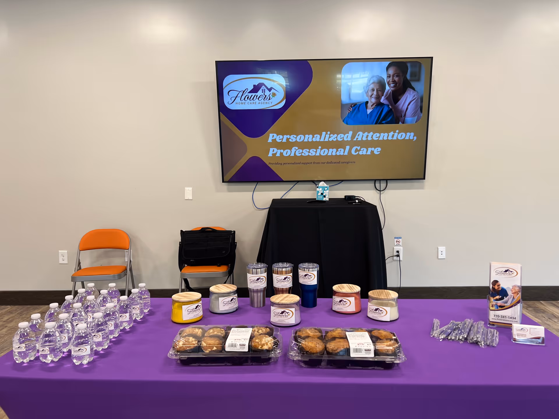 Event setup in a conference room with refreshments and a large Flowers Home Care display.