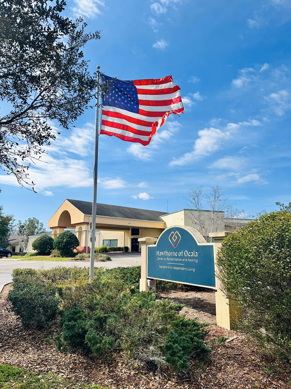 American flag waves beside Hawthorne of Ocala entrance sign and single-story building.