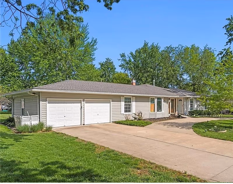 Front exterior of a single-story house with a two-car garage and green lawn.