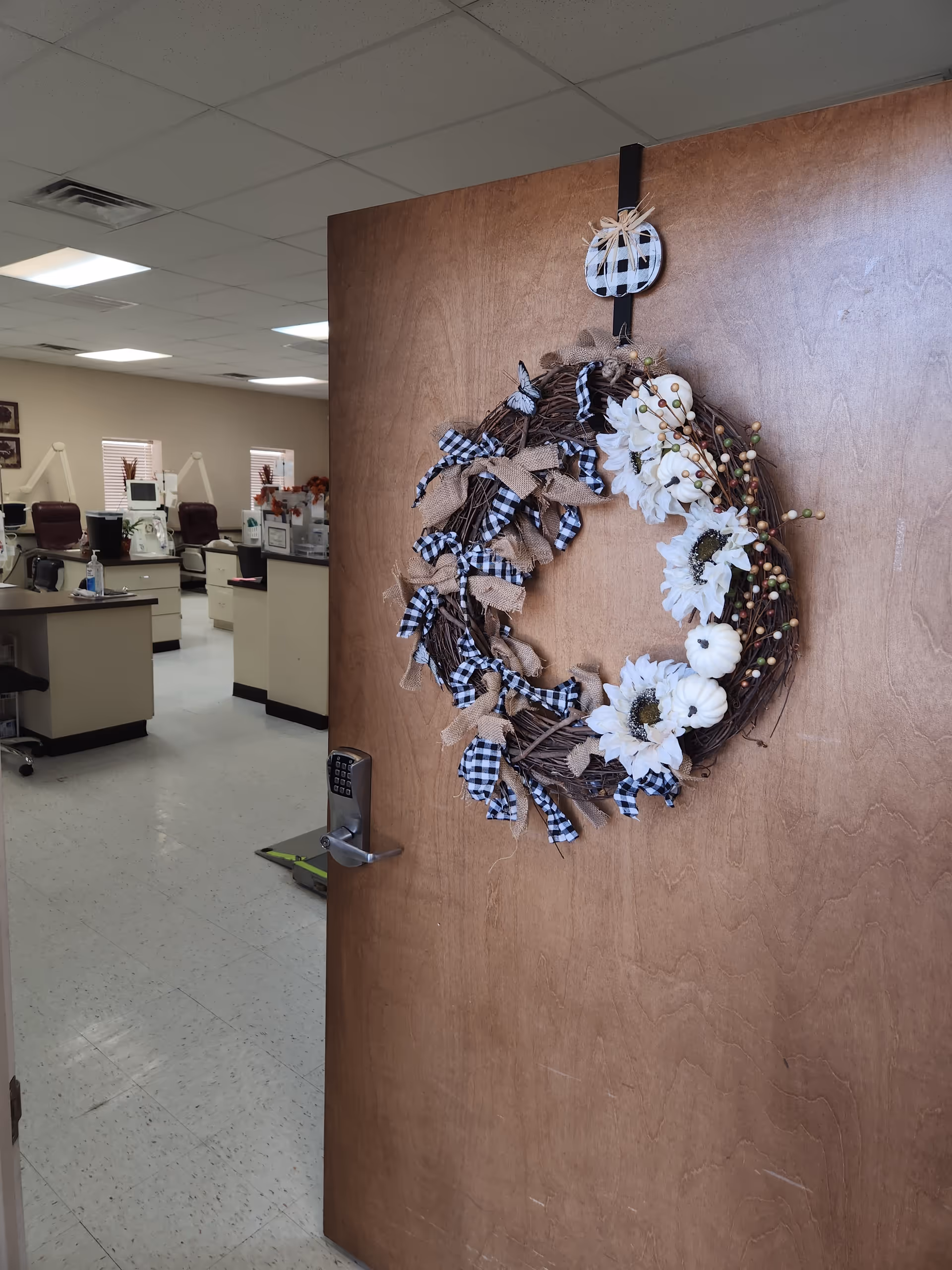 Wooden door decorated with a wreath opens to an office-like reception area.