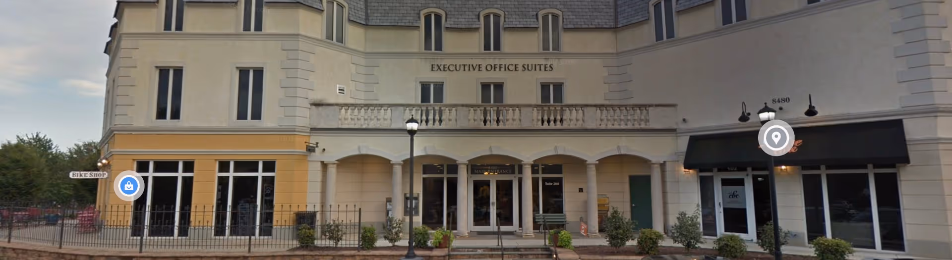 Front view of a beige building with arched entrance labeled Executive Office Suites.