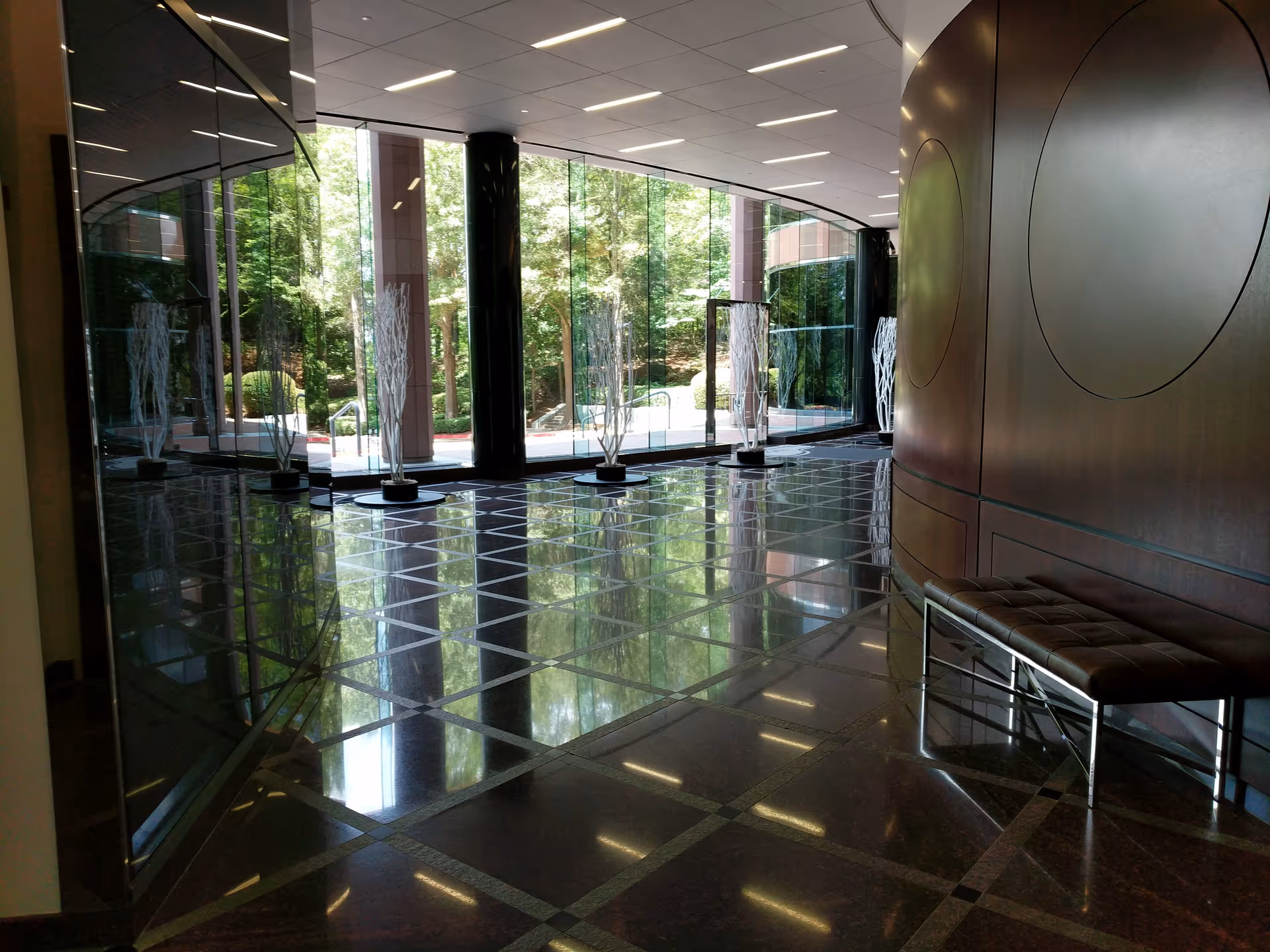 Avant Care lobby with glass walls, polished floors, decorative trees, and a curved metal wall.