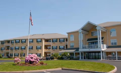 Exterior view of The Village at South Farms with a flagpole and manicured landscaping.