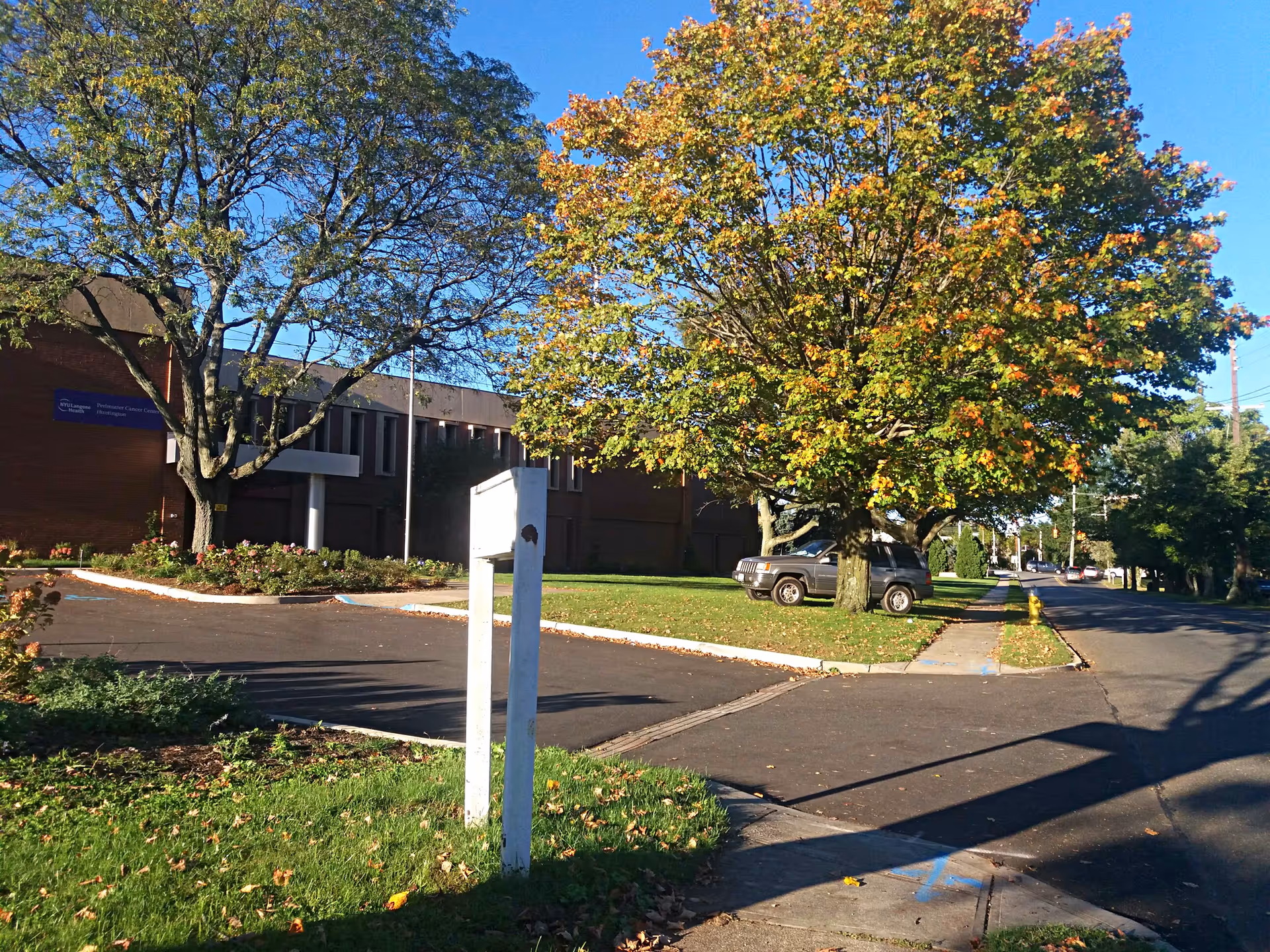 Exterior view of a medical building with trees, parking lot, and blue sky.