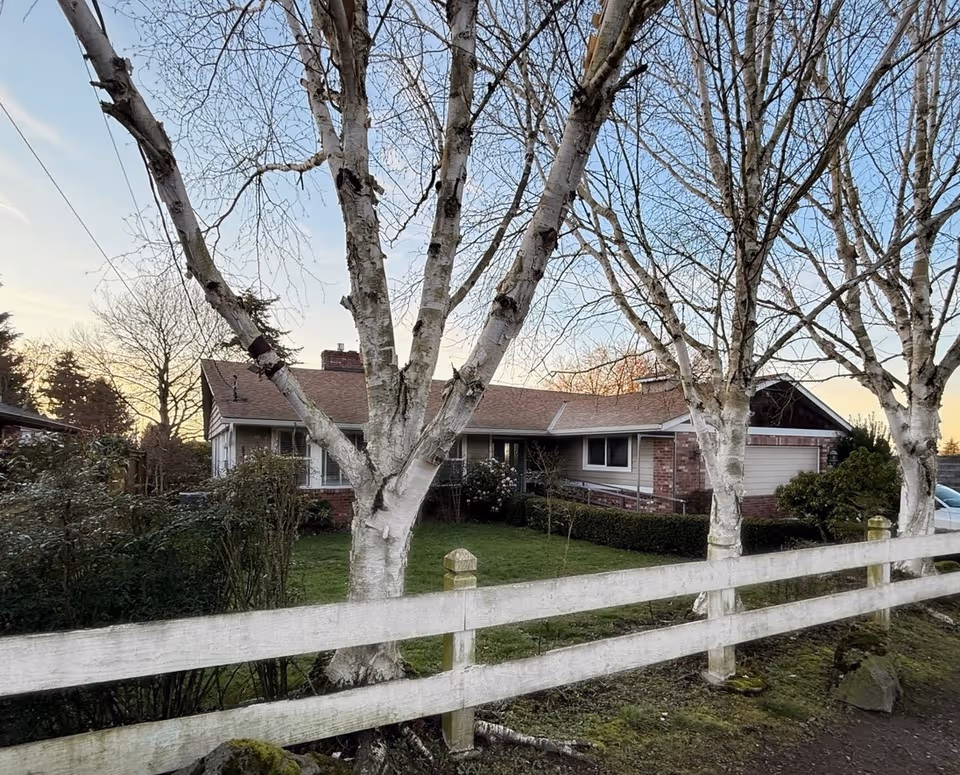 Front exterior of Langland House with bare trees and a white wooden fence.