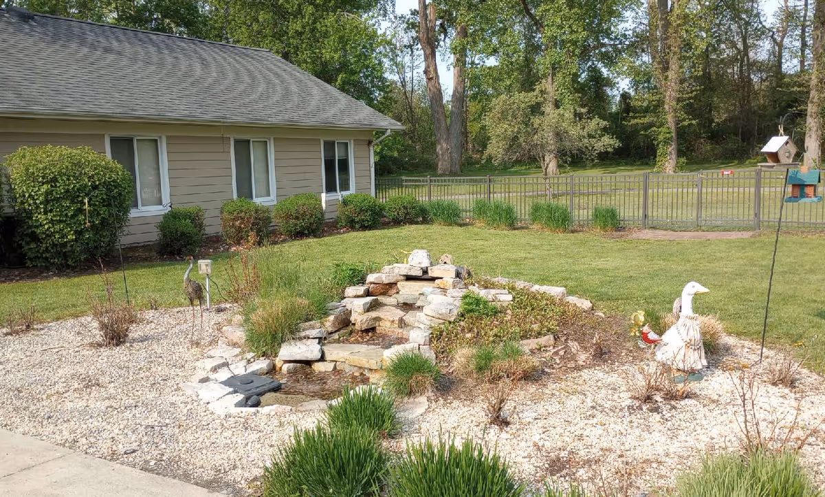 Exterior view of Vibrant Life of Temperance showing a rock waterfall garden, lawn, and duck statues.